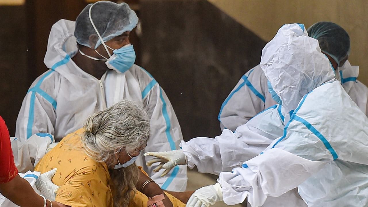 Health workers wearing PPE suit help a patient during admission at a COVID hospital during the ongoing Covid-induced lockdown, in Kolkata. Credit: PTi Photo