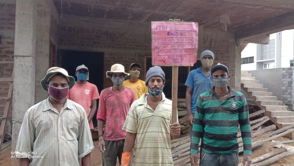 Construction labourers stage a protest at their worksite, holding a placard with their demands, in Kodlipete.
