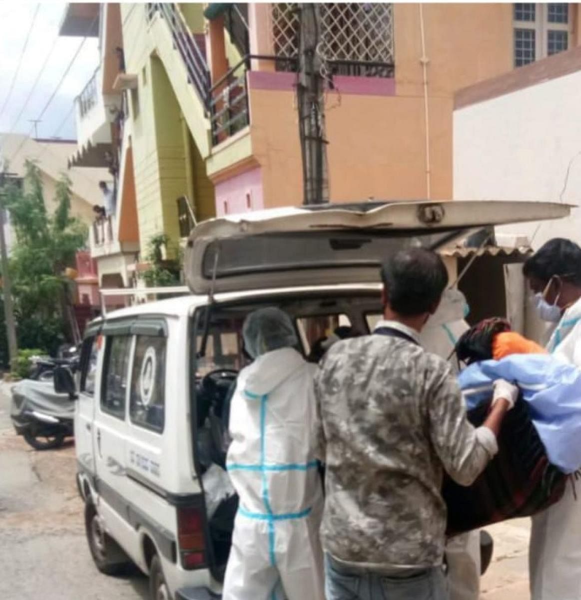 Mysuru City Corporation employees shift the body of the woman at Mahadeshwara Layout in Mysuru on Friday. DH Photo