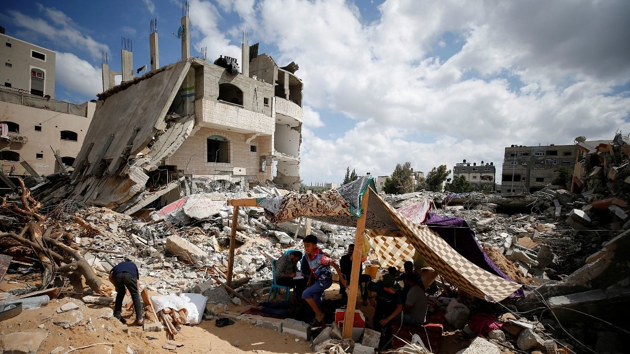 Palestinians sit in a makeshift tent amid the rubble of their houses which were destroyed by Israeli air strikes during the Israel-Hamas fighting in Gaza May 23, 2021. Credit: Reuters Photo