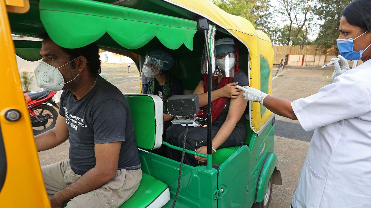 A medical worker inoculates a girl sitting inside an auto rickshaw with a dose of the Covishield Covid-19 vaccine during a special drive-in vaccination camp held in Bhopal. Credit: AFP Photo