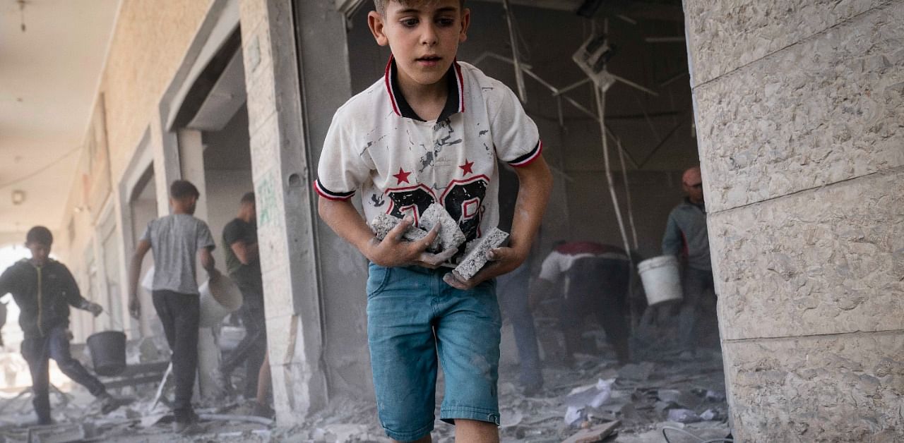 Children scavenge debris from a severely damaged building. Credit: AP Photo