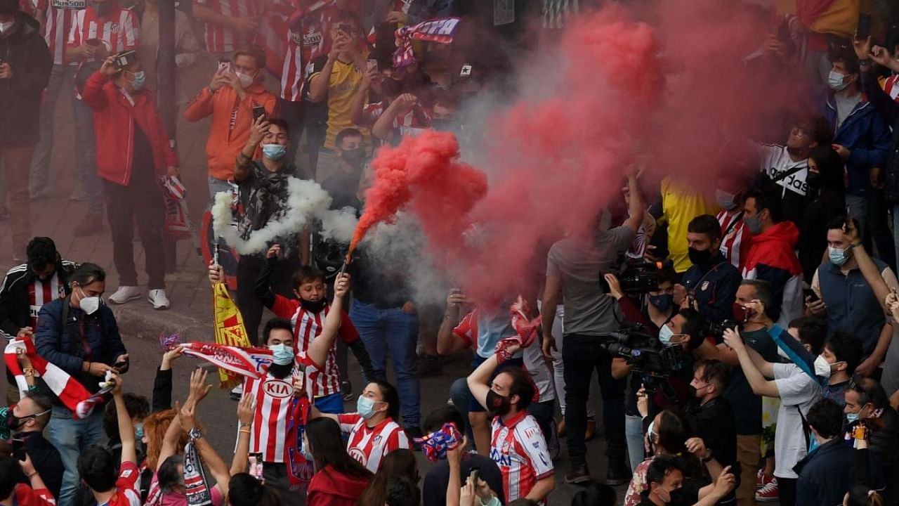 Supporters light flares after Atletico Madrid won the Spanish Liga Championship title on May 22, 2021 in Madrid. Credit: AFP Photo