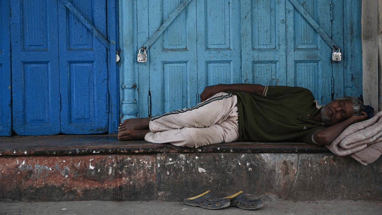 A man sleeps outside a closed shop during a lockdown imposed as preventive measure against the spread of the Covid-19, in the old quarters of New Delhi. Credit: AFP Photo