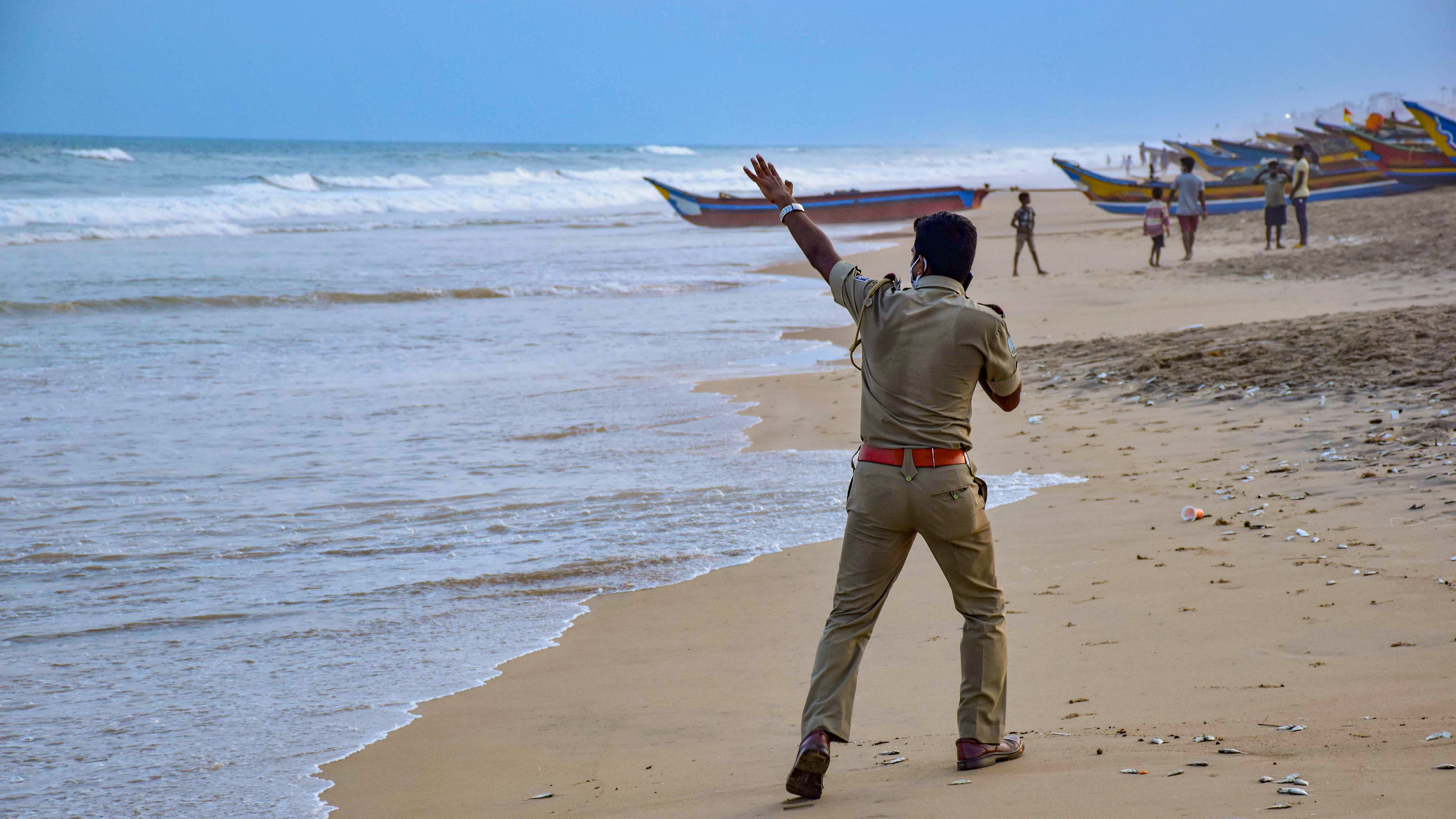 A police person announces cyclone related warnings at a beach in Puri, Saturday. Credit: PTI