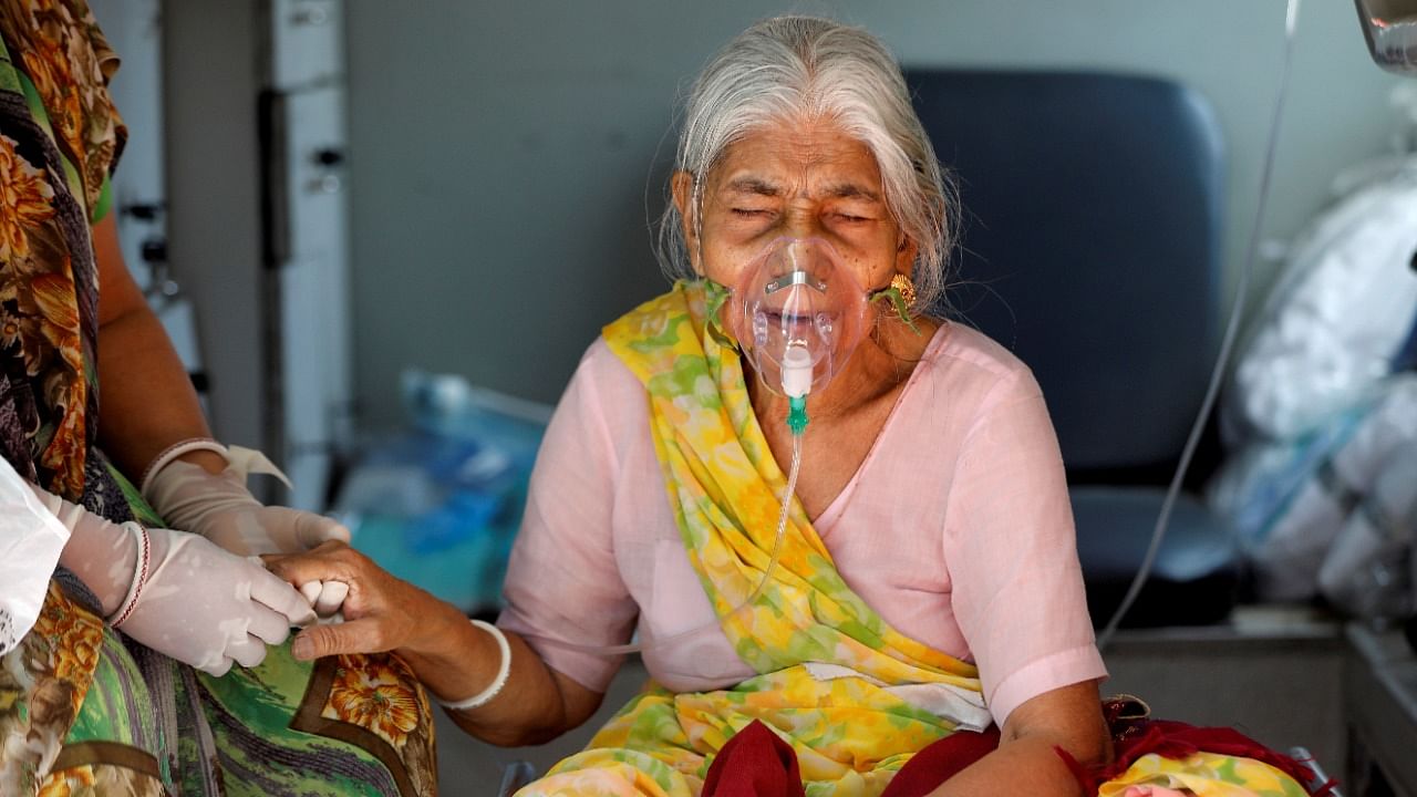 An elderly woman wearing an oxygen mask, sits inside an ambulance as she waits to enter a Covid-19 hospital for treatment. Credit: Reuters Photo