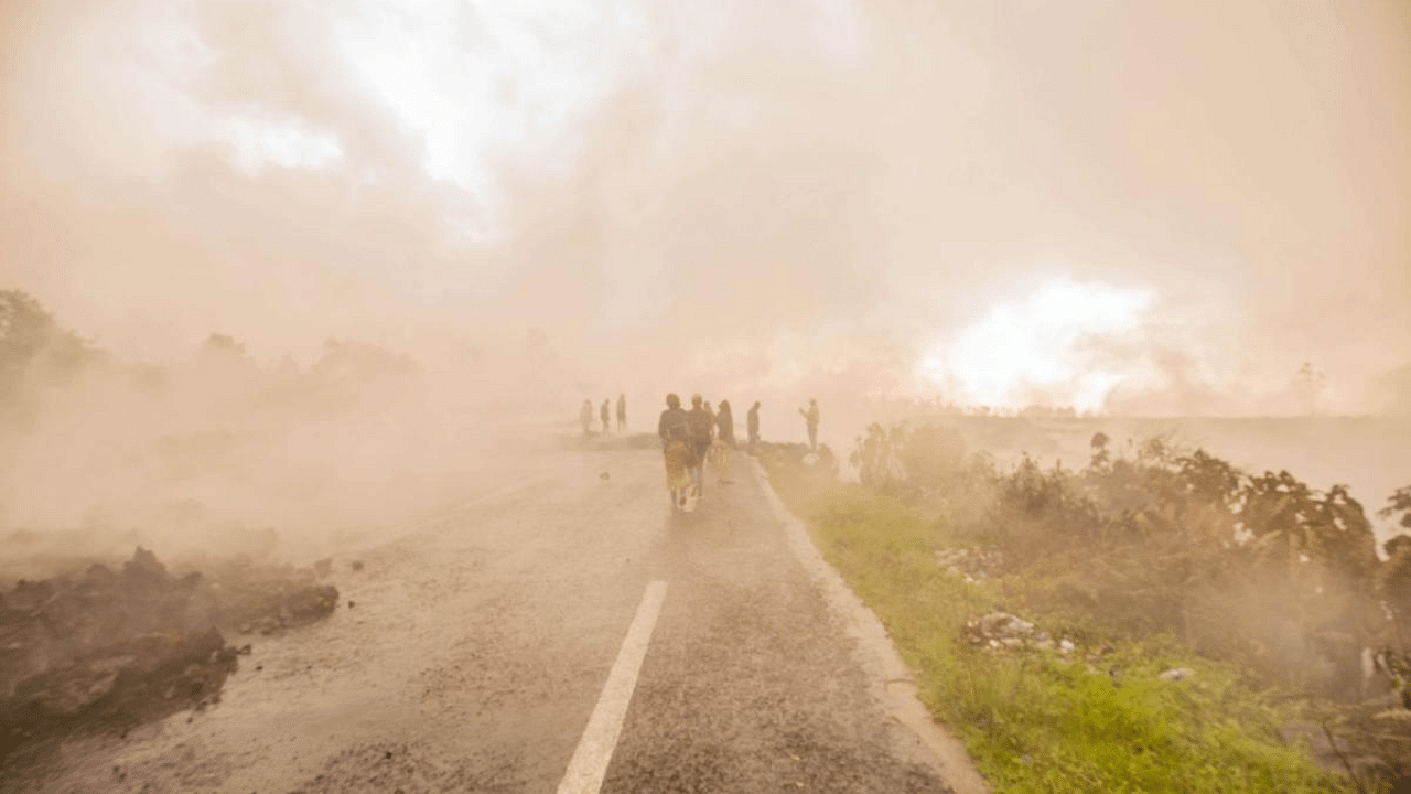 Residents walk through the smoke from smouldering lava flewing from Mount Nyiragongo in Goma. Credit: AFP Photo