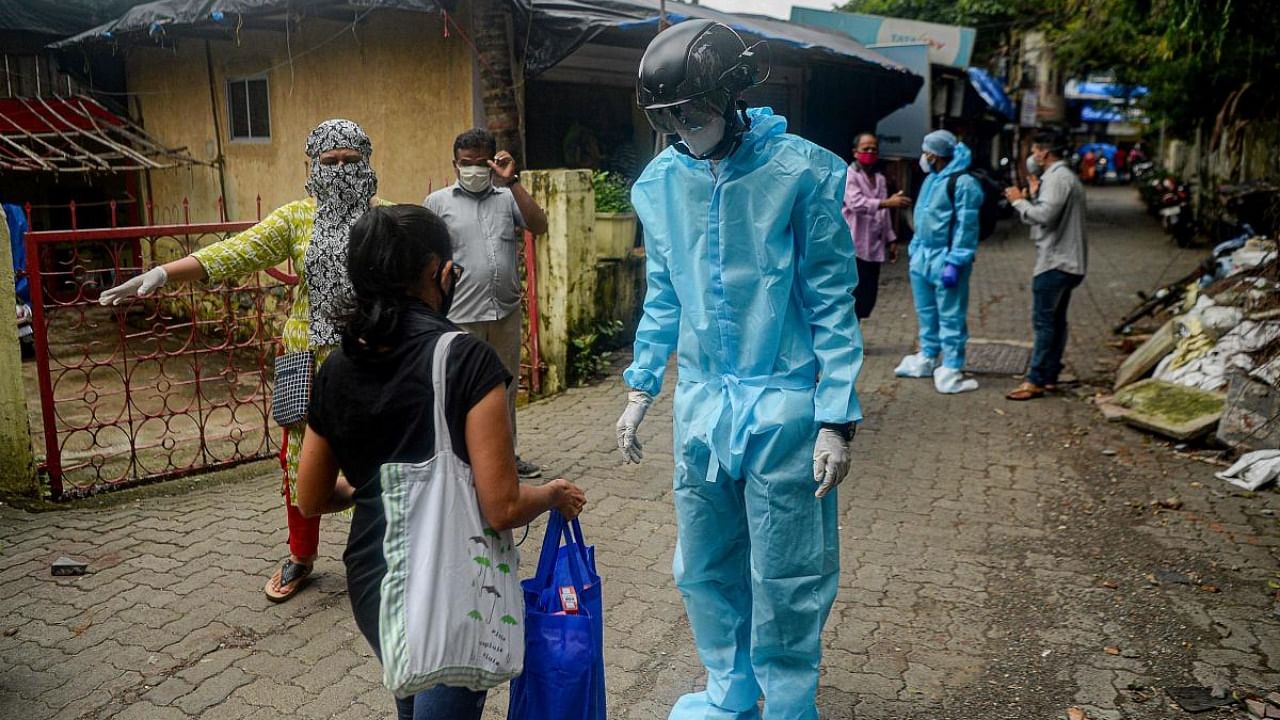 A volunteer health worker of the Non-Governmental Organization (NGO) Bharatiya Jain Sanghatana (BJS) wearing Personal Protective Equipment (PPE) using a smart helmet equipped with a thermo-scan sensor checks the body temperature of residents during a door-to-door medical screening drive for the COVID-19 coronavirus, at a residential area in Mumbai on July 21, 2020. Cedit: AFP Photo