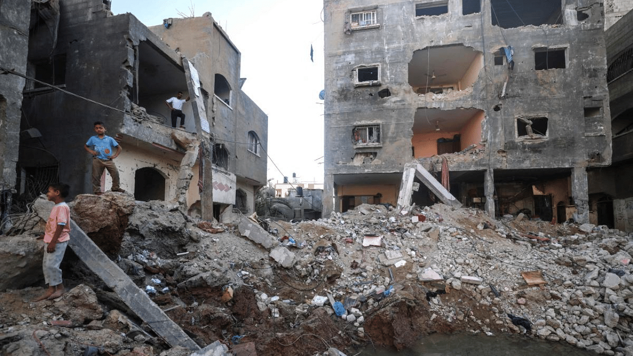 Palestinian children walk through the rubble next to a crater. Credit: AFP Photo