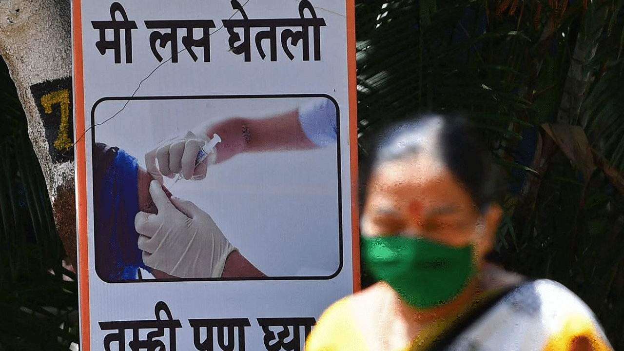 A woman walks past a poster at a Covid-19 vaccination centre in Mumbai. Credit: AFP Photo