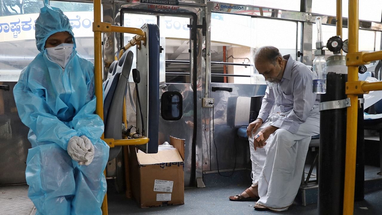 A health worker keeps a check on a Covid-19 patient recieving oxygen in a bus, in Bengaluru, Saturday, May 15, 2021. Credit: PTI Photo