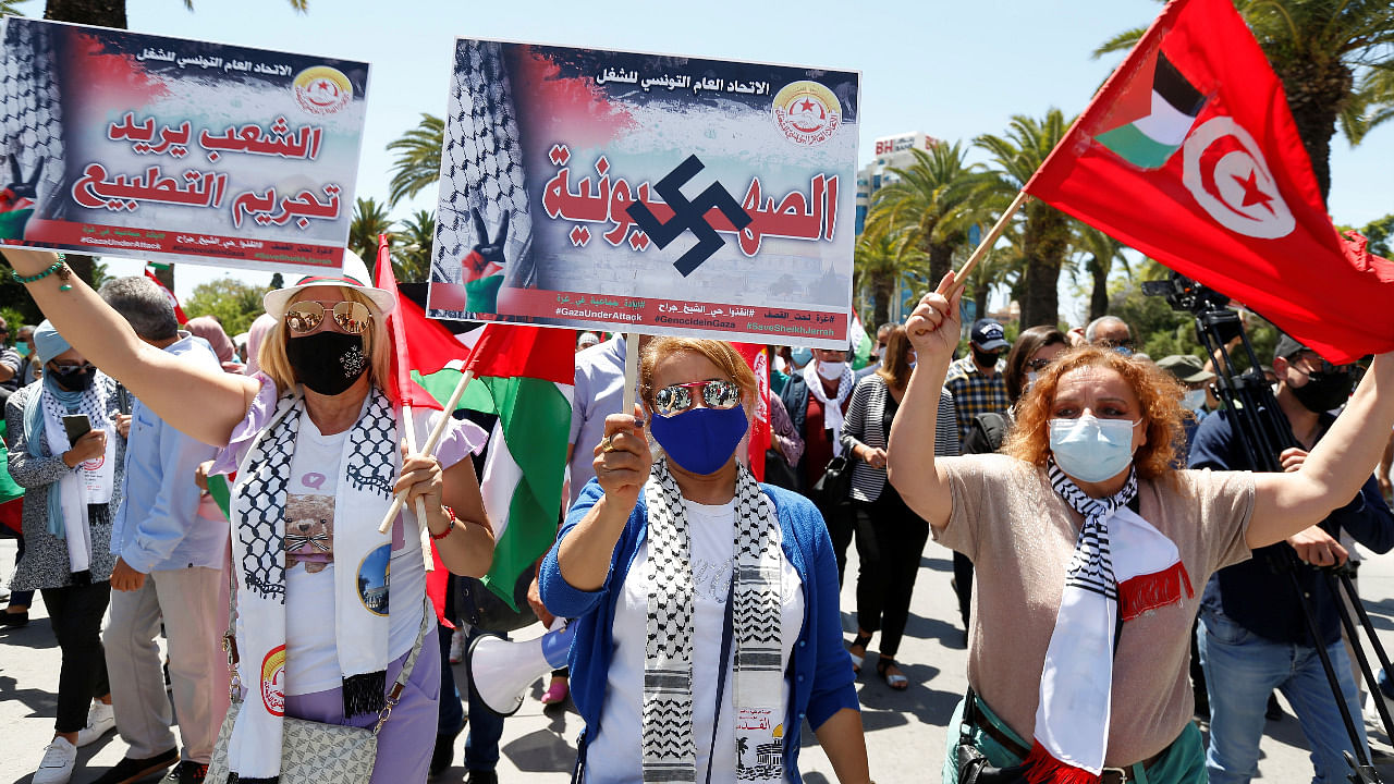 Demonstrators hold placards reading ''The people want to criminalise normalisation'' and ''Zionism'' during a protest to express solidarity with the Palestinian people, in Tunis, Tunisia. Credit: Reuters Photo