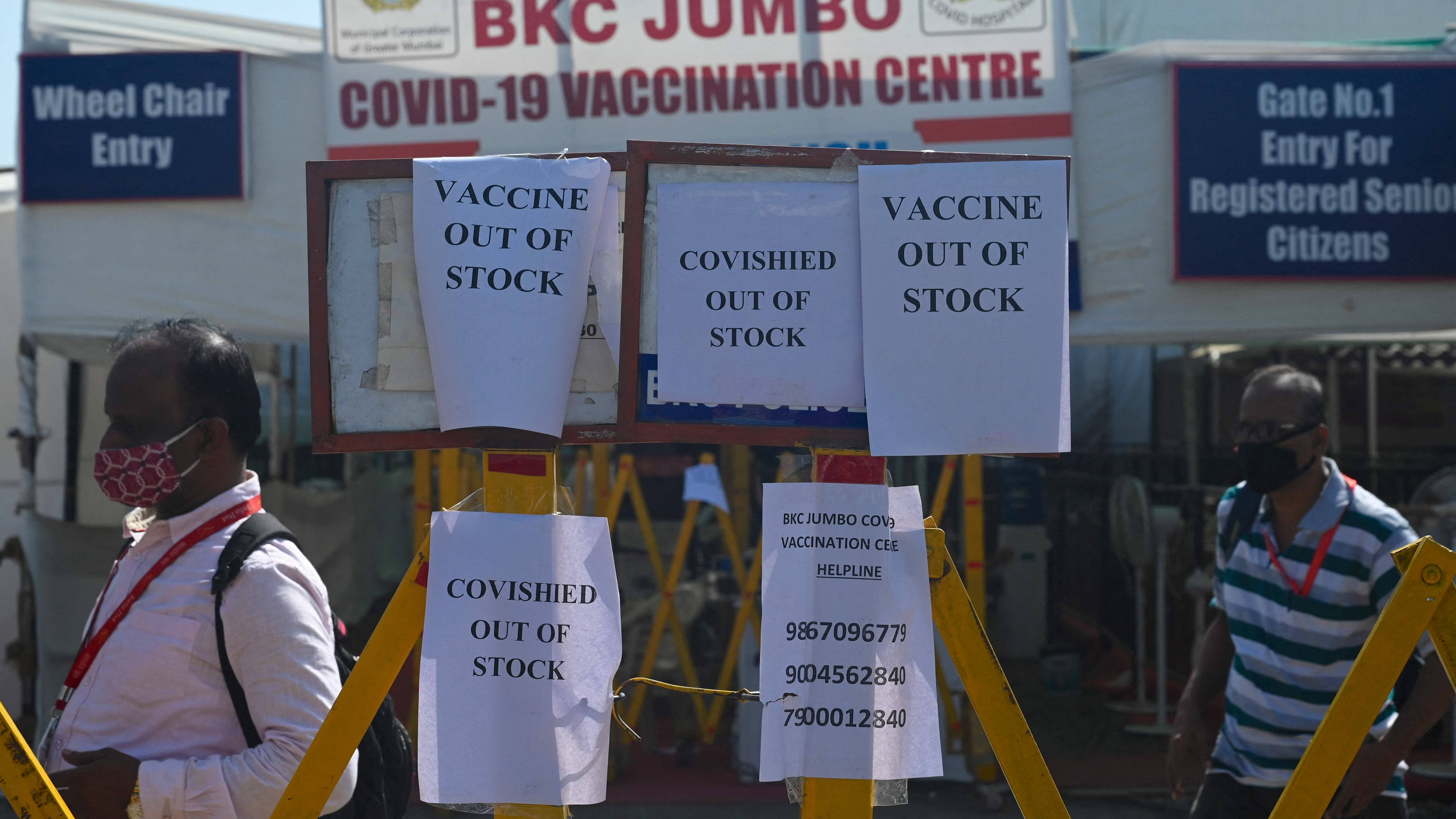 People walk past notices announcing that the Covishield, AstraZeneca-Oxford's Covid-19 coronavirus vaccine is out of stock at a vaccination centre in Mumbai. Credit: AFP File Photo