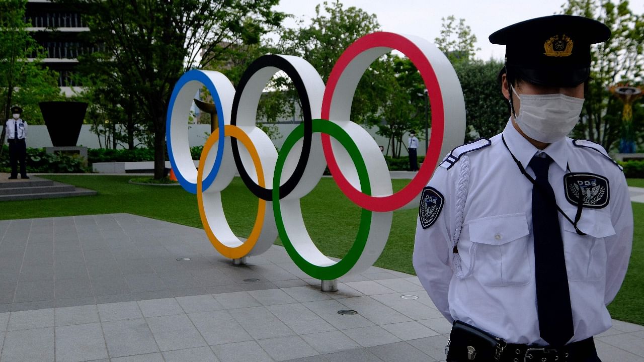 In this file photo taken on May 18, 2021, security guards keep watch next to the Olympic Rings while people take part in a protest against the hosting of the 2020 Tokyo Olympic Games, in front of the headquarters building of the Japanese Olympic Committee in Tokyo. Credit: AFP Photo