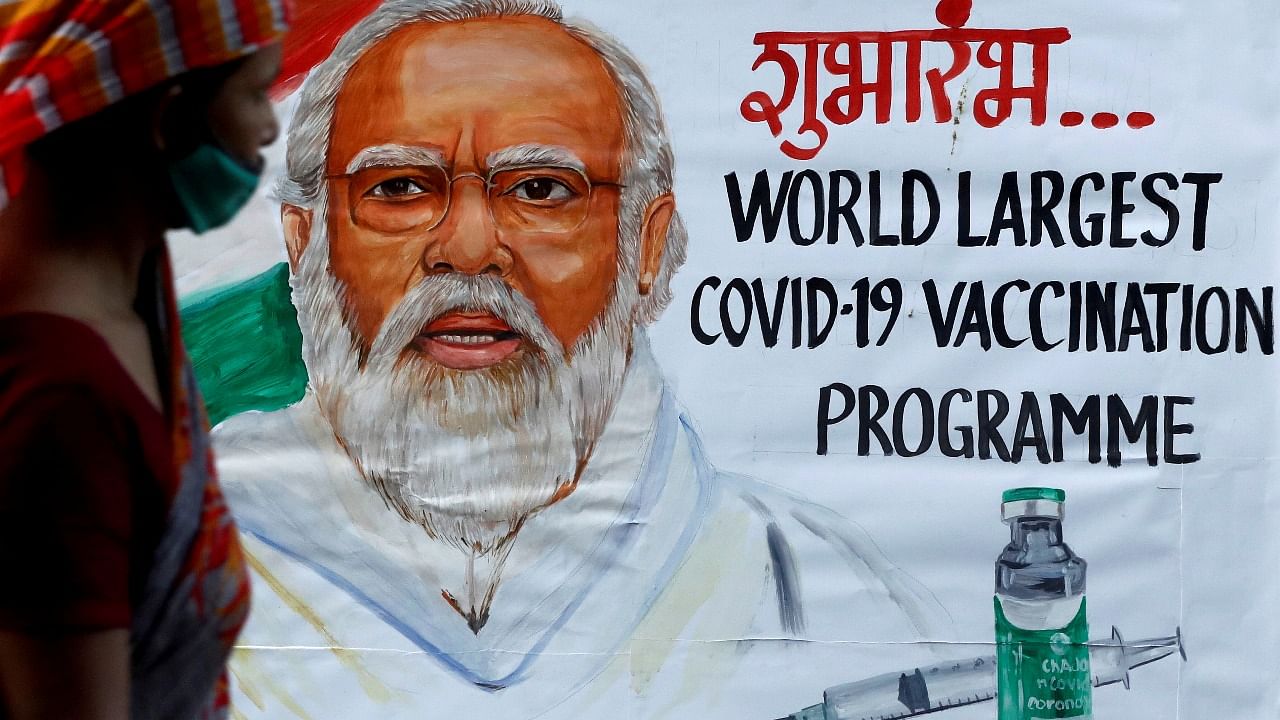 A woman walks past a painting of Indian Prime Minister Narendra Modi in Mumbai a day before inauguration of India's Covid-19 vaccination drive. Credit: Reuters photo