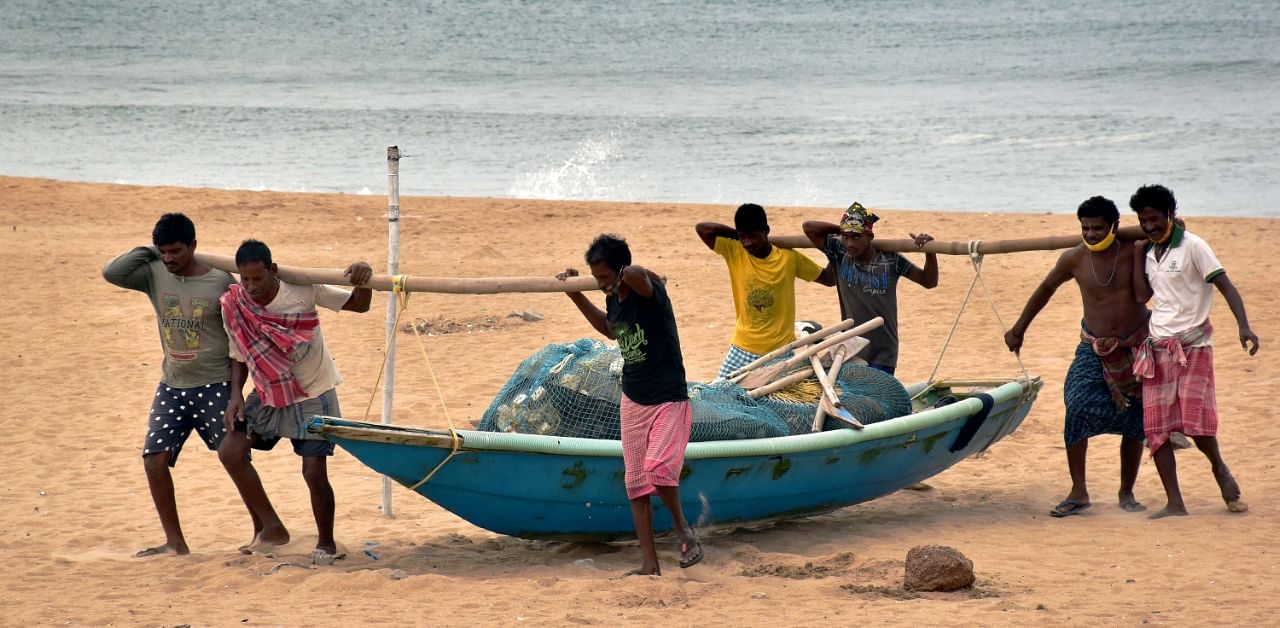 Fishermen carry a boat to a safe place ahead of cyclone Yaas at Puri beach. Credit: PTI Photo