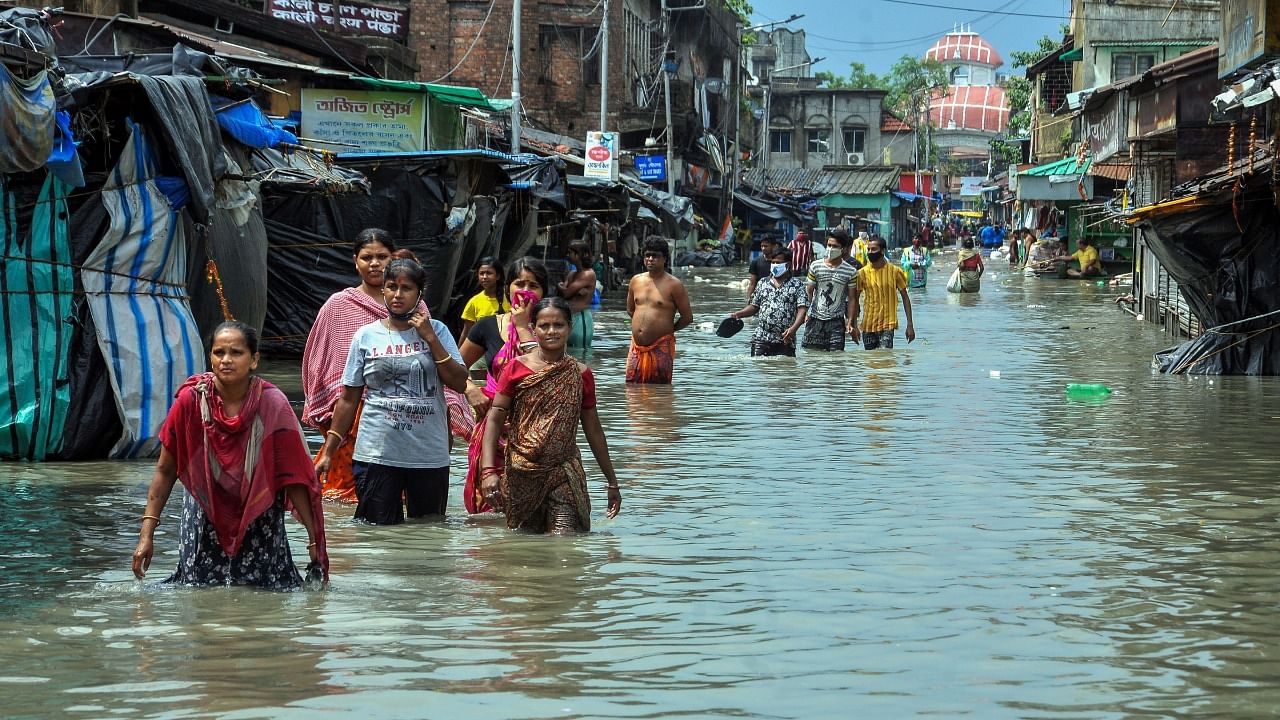 Pedestrians wade through a flooded road during landfall of cyclone 'Yaas', in Kolkata. Credit: PTI Photo