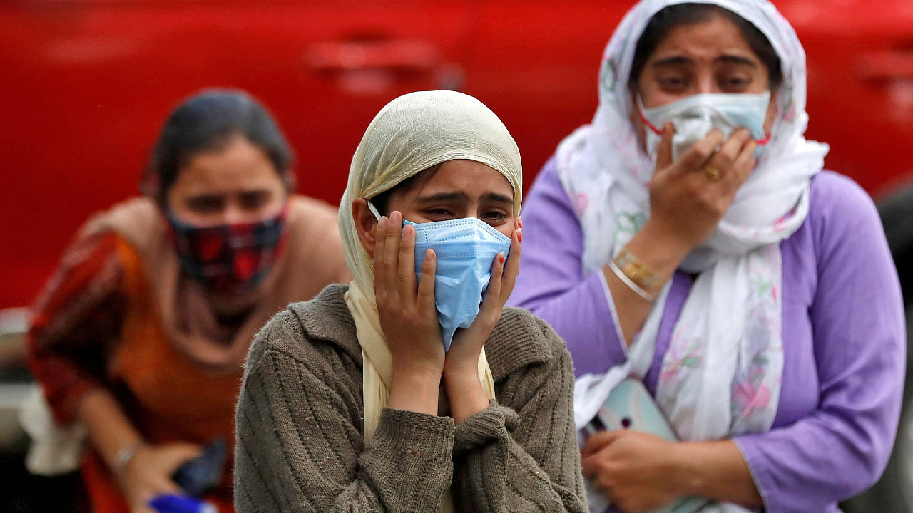 Relatives of a man who died from the coronavirus disease (COVID-19) mourn during his cremation at a crematorium ground in Srinagar. Credit: Reuters Photo