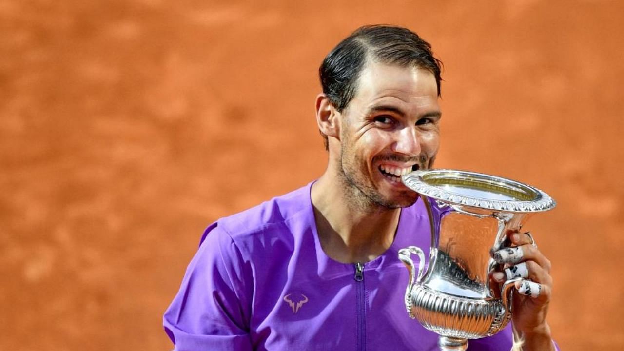 Spain's Rafael Nadal bites the winner's trophy after defeating Serbia's Novak Djokovic during the final of the Men's Italian Tennis Open at Foro Italico on May 16, 2021 in Rome, Italy. Credit: AFP Photo
