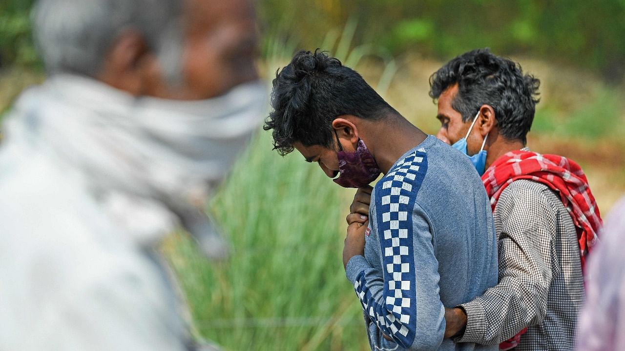 In this picture taken on May 5, 2021, the son (C) of a science school teacher, who died of the Covid-19 coronavirus grieves after lighting his father's funeral pyre at a crematorium in Moradabad. Credit: AFP Photo