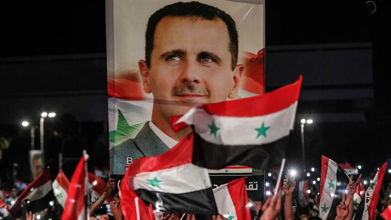 Syrians wave national flags and a large portrait of their president as they celebrate in the streets of the capital Damascus, a day after an election set to give the current President Bashar al-Assad a fourth term. Credit: AFP Photo