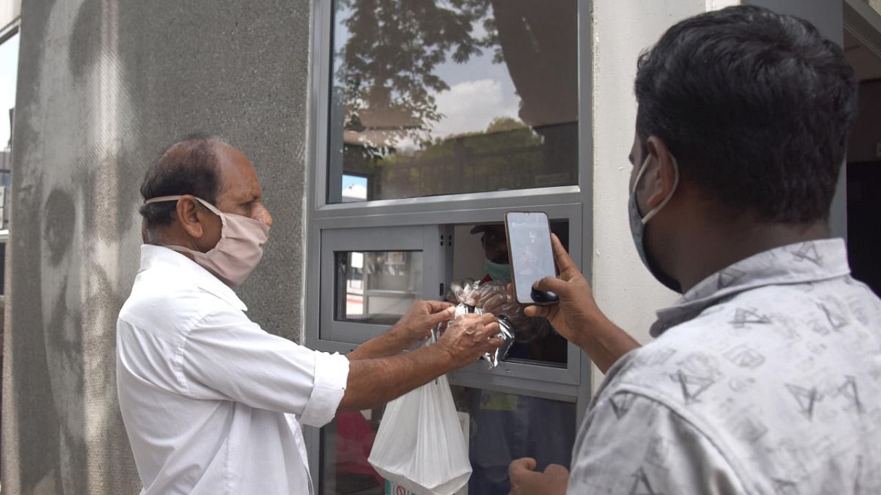 Supervisor of an Indira Canteen records people receiving free food, at Gubbi Thotadappa road, near Majestic metro railway station in Bengaluru on Wednesday, 26 May 2021. Credit: DH Photo/S K Dinesh