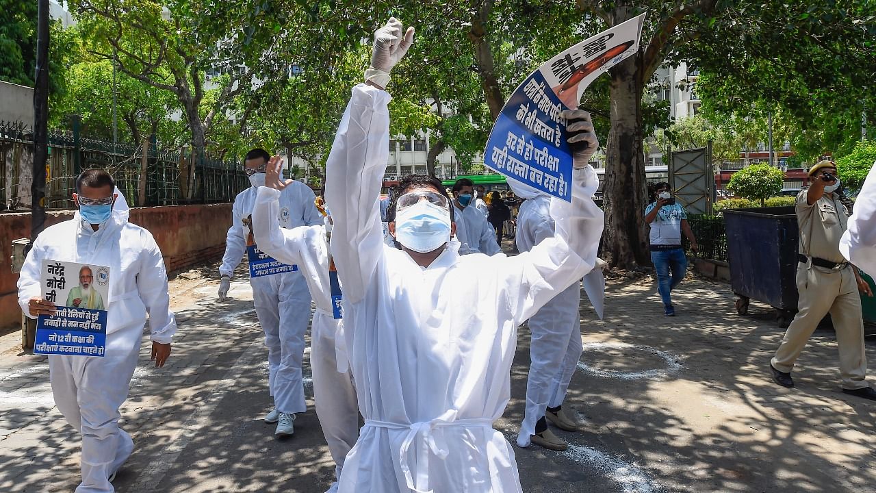 Members of National Students Union of India (NSUI), wearing PPE kits, stage a protest demanding cancellation of board exams, outside MHRD office in New Delhi. Credit: PTI Photo