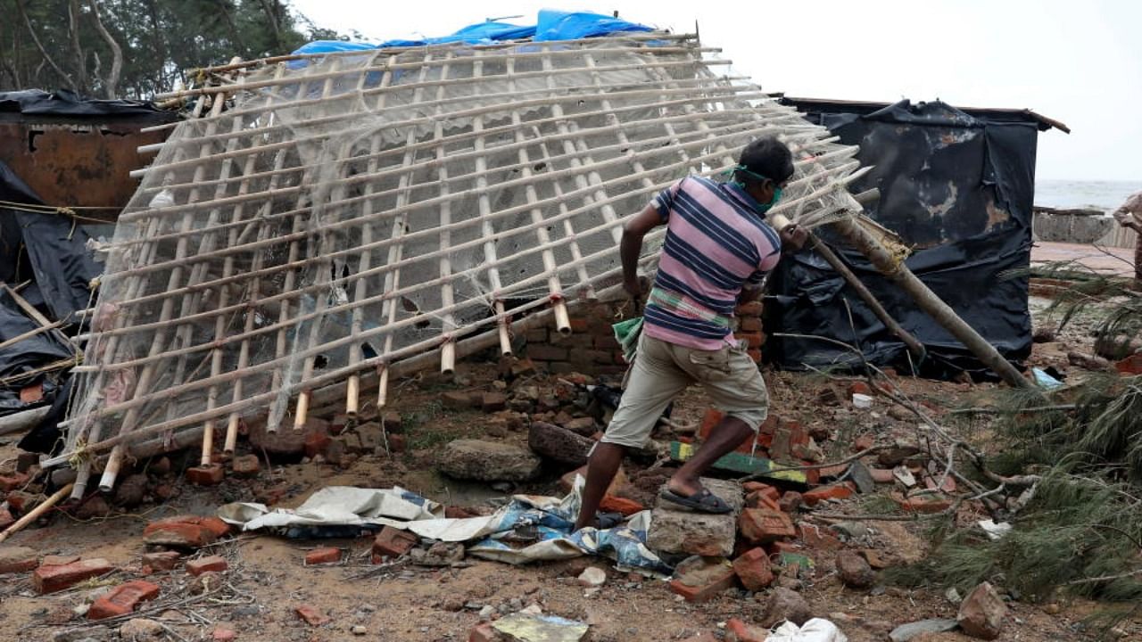 A man removes a bamboo rooftop of a damaged hut following Cyclone Yaas in Digha, Purba Medinipur district, in West Bengal. Credit: Reuters Photo