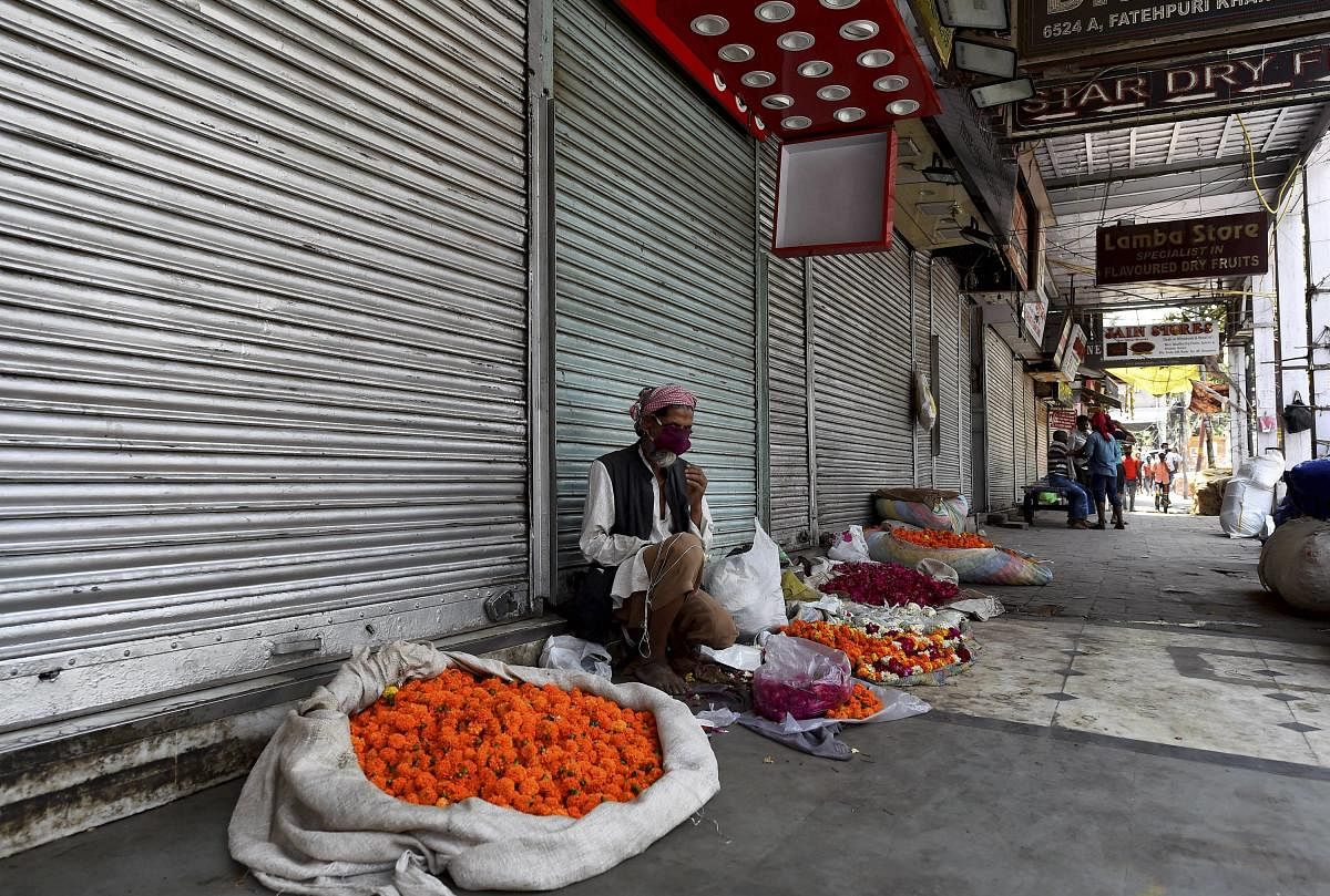 A man sells flowers outside a closed shop during Covid-induced lockdown, at Khari Baoli market in New Delhi. Credit: PTI Photo