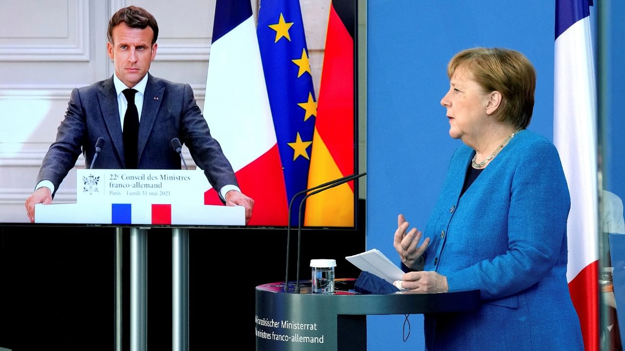 French President Emmanuel Macron is seen on a video screen during a joint press conference with German Chancellor Angela Merkel. Credit: Reuters Photo
