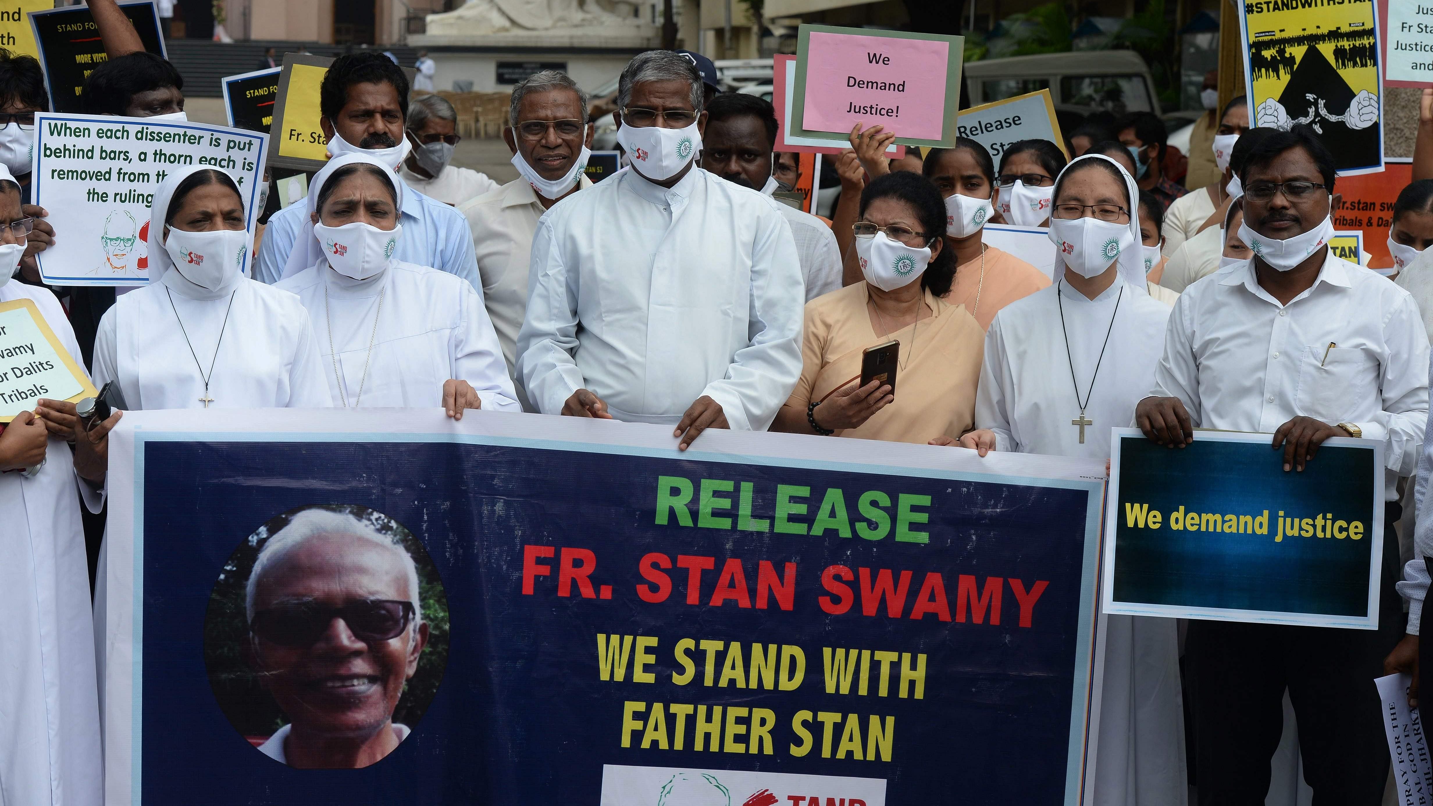 Catholic priests and nuns hold a banner during a protest against the arrest of Jesuit priest Father Stan Swamy. Credit: AFP File Photo