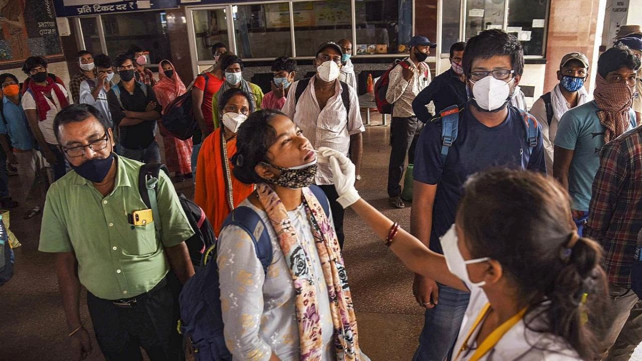 A health worker collects swab sample from a passenger for Covid-19 testing at Patna railway station, in Patna. Credit: PTI Photo