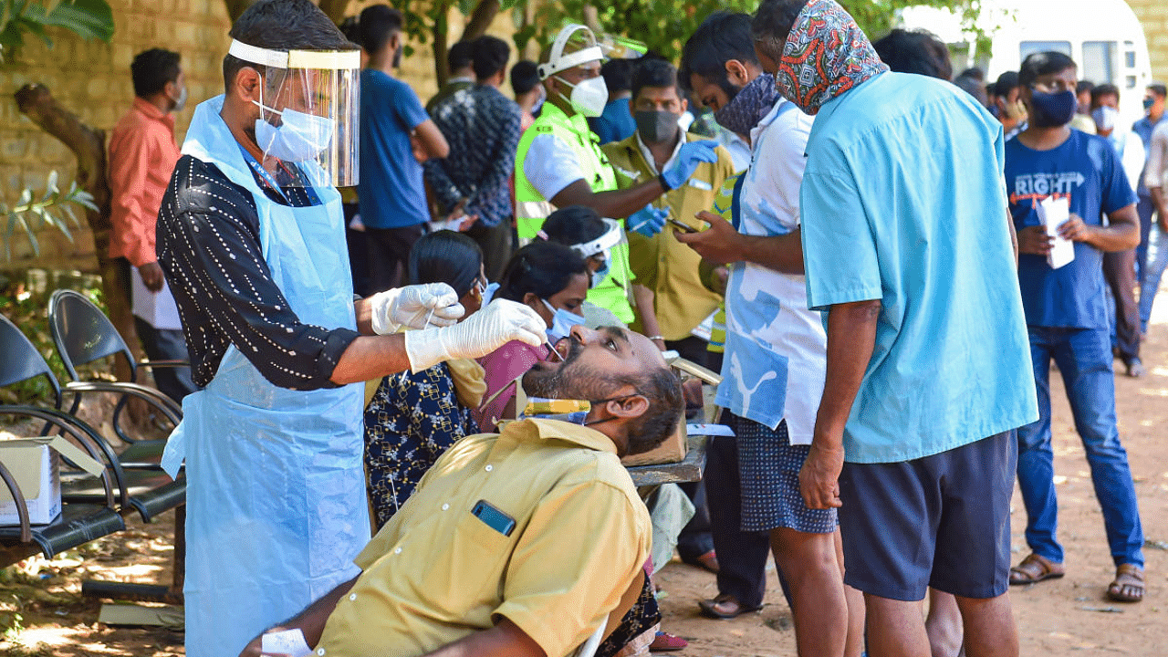 A medic collects a swab sample from a man for the Covid-19 testing, in Bengaluru. Credit: PTI Photo