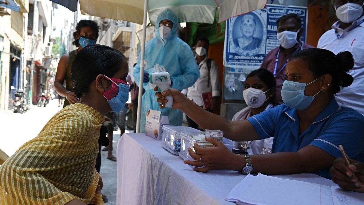 A health worker checks the body temperature of a woman as a preventive measure against the Covid-19 coronavirus at residential area in Chennai. Credit: AFP Photo