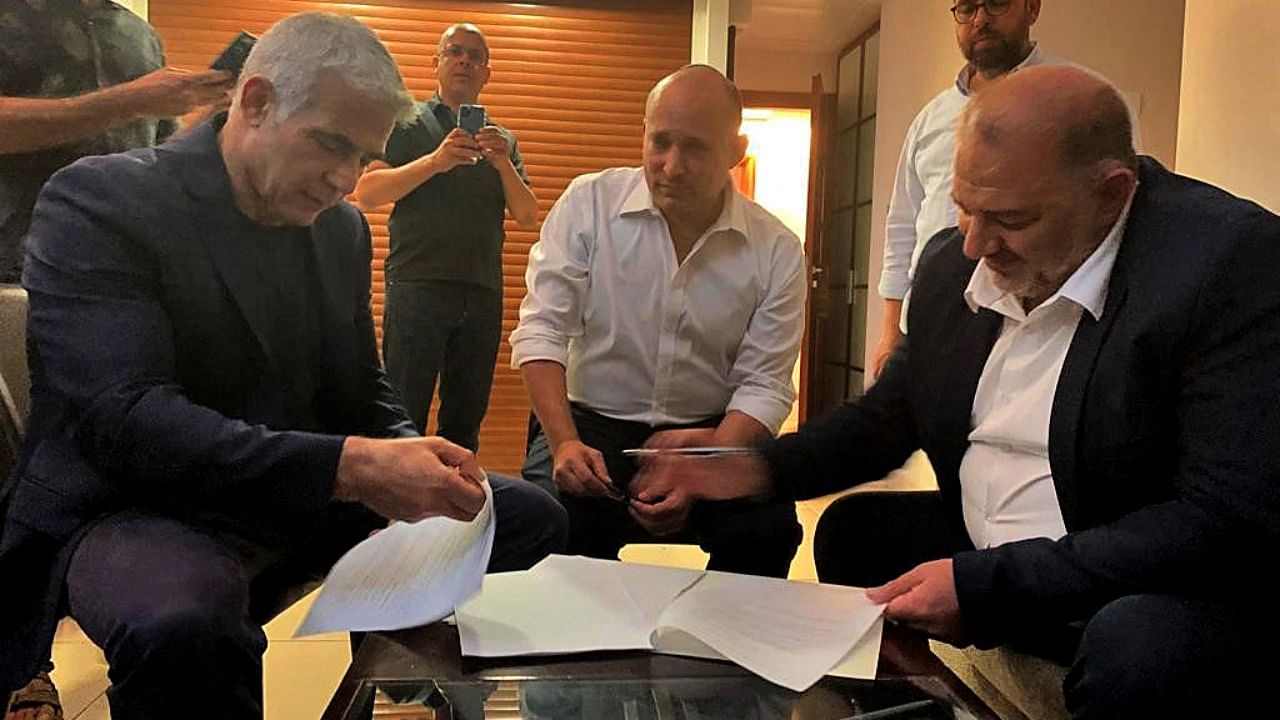 Head of the Arab Israeli Islamic conservative party Raam Mansour Abbas (R) signs a coalition agreement with Israel's opposition leader Yair Lapid (L) and right-wing nationalist tech millionaire Naftali Bennett in Ramat Gan near the coastal city of Tel Aviv. Credit: AFP Photo/HO/RAAM