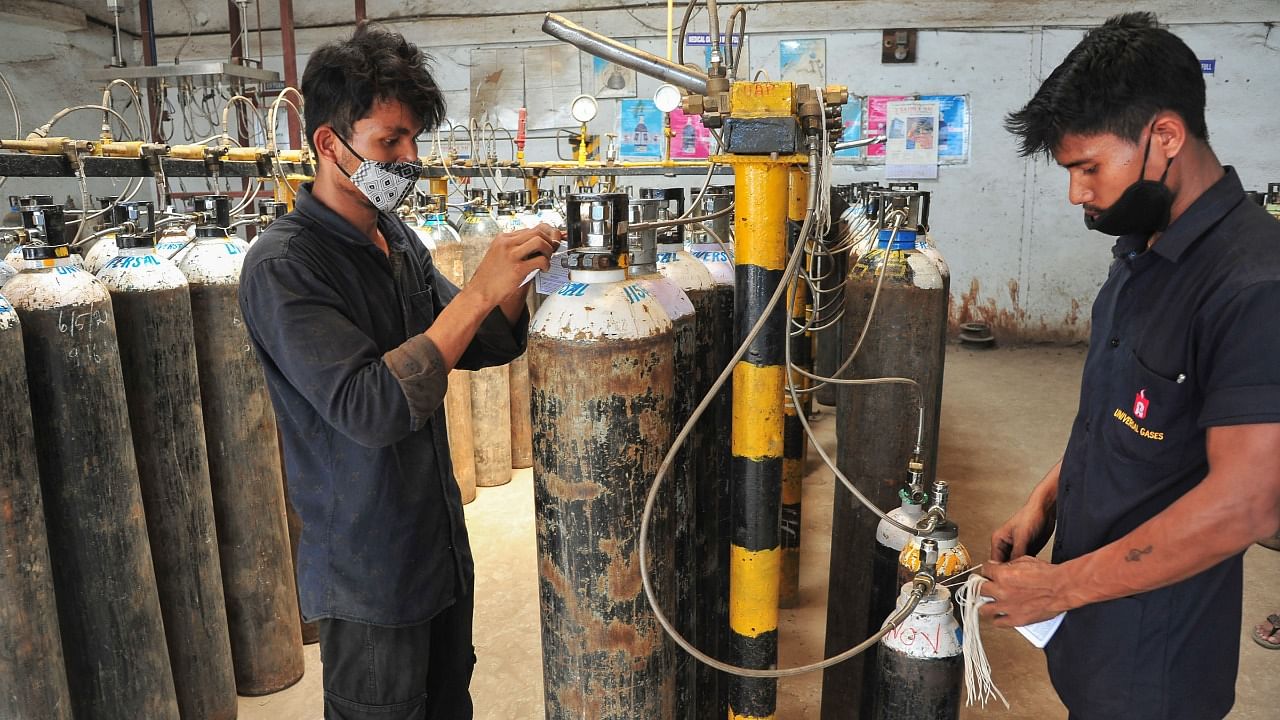 Workers refill medical oxygen cylinders meant for Covid-19 patients, before dispatching them to hospitals, at a facility amid surge in coronavirus cases, in Bengaluru, Thursday, May 6, 2021. Credit: PTI Photo