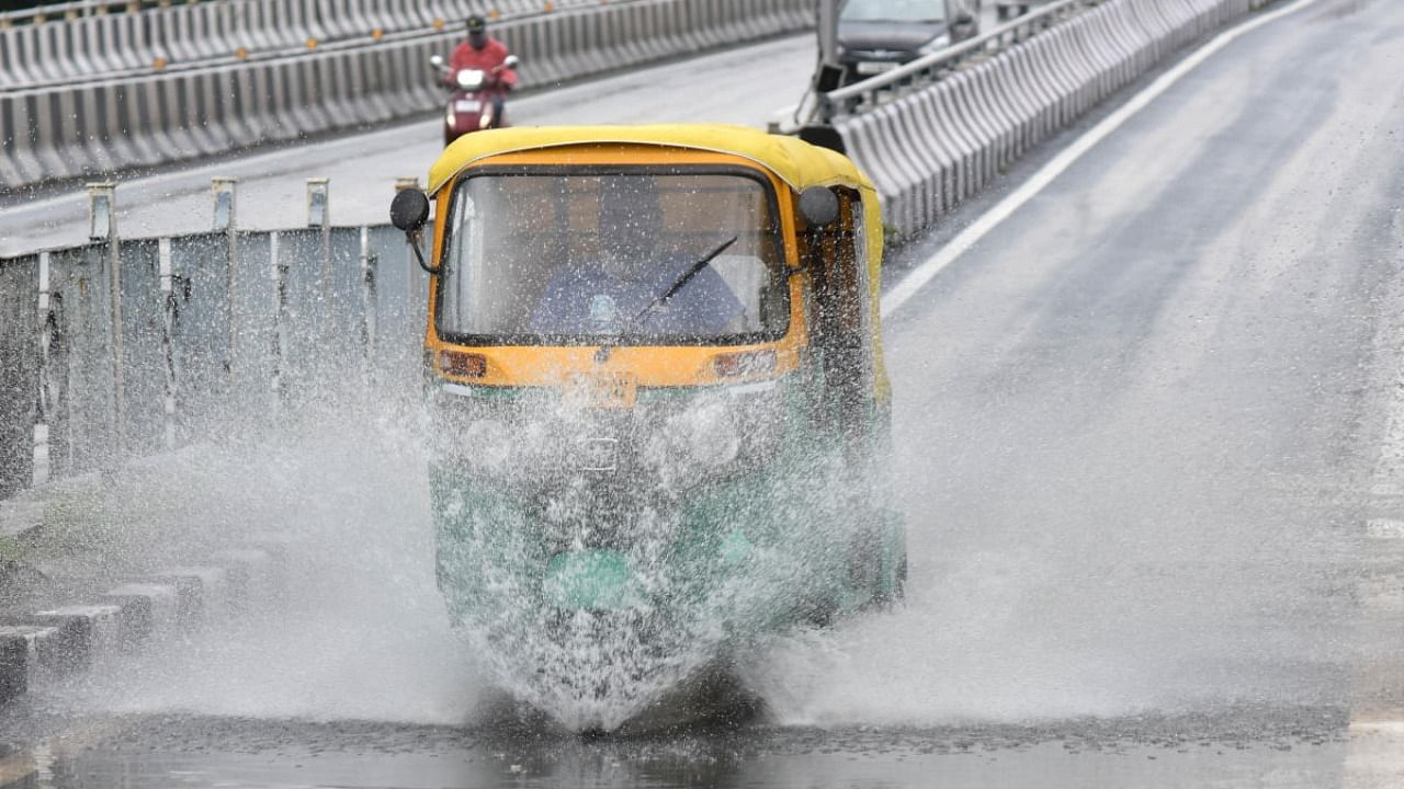 An auto-rickshaw drive navigates a rain-filled Hebbal flyover in Bengaluru on Thursday. Credit: DH Photo/JANARDHAN B K
