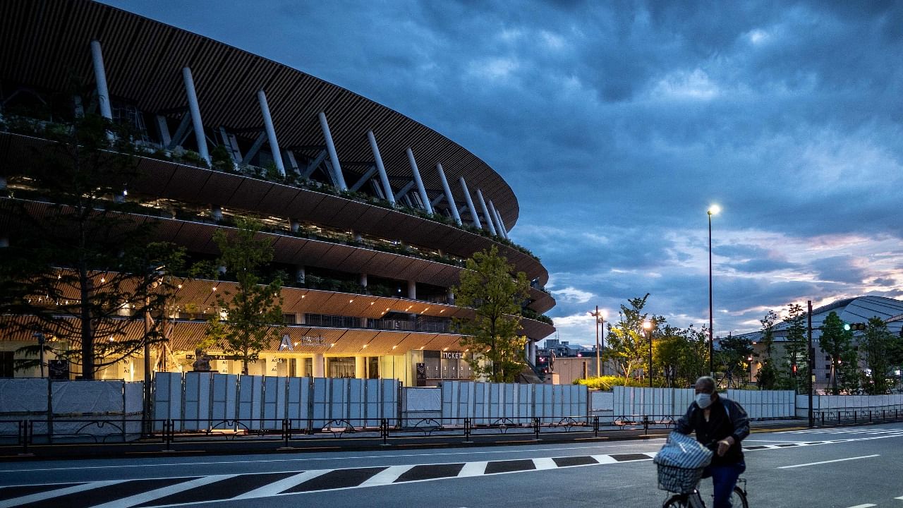 A man rides his bike near the National Stadium, main venue for the Tokyo Olympic and Paralympic Games in Tokyo. Credit: AFP Photo