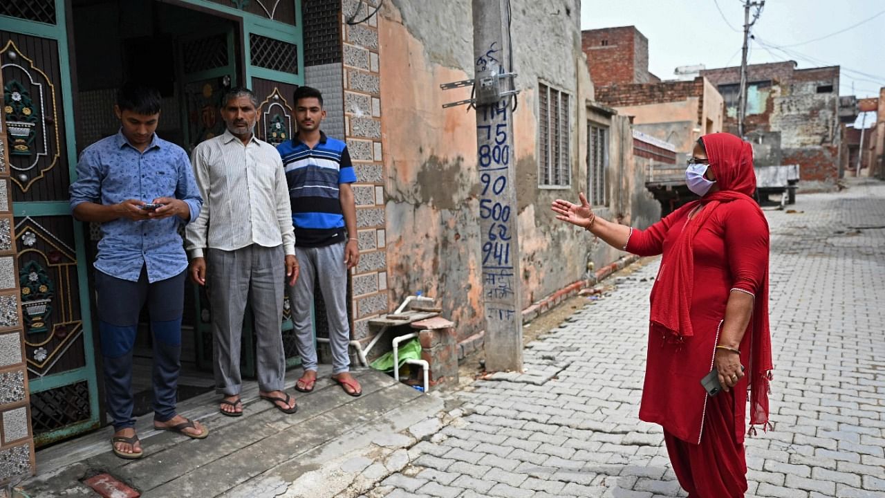 An ASHA worker (R) speaks to a family during a door-to-door Covid-19 vaccine awareness campaign in Kalwa. Credit: AFP Photo