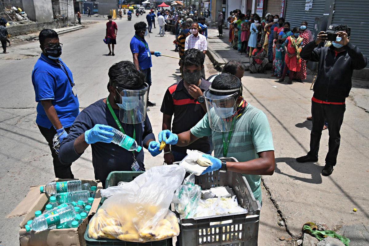 NGOs distribute free food and face masks to the needy near KR Market in Bengaluru on Sunday. Credit: DH Photo/Pushkar V