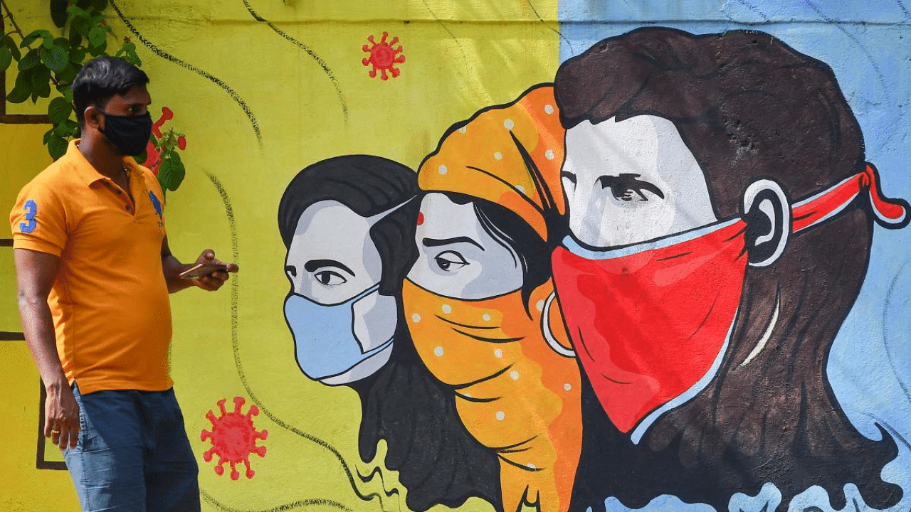 A pedestrian walks past a wall mural representing awareness measures against the coronavirus in Navi Mumbai. Credit: AFP Photo