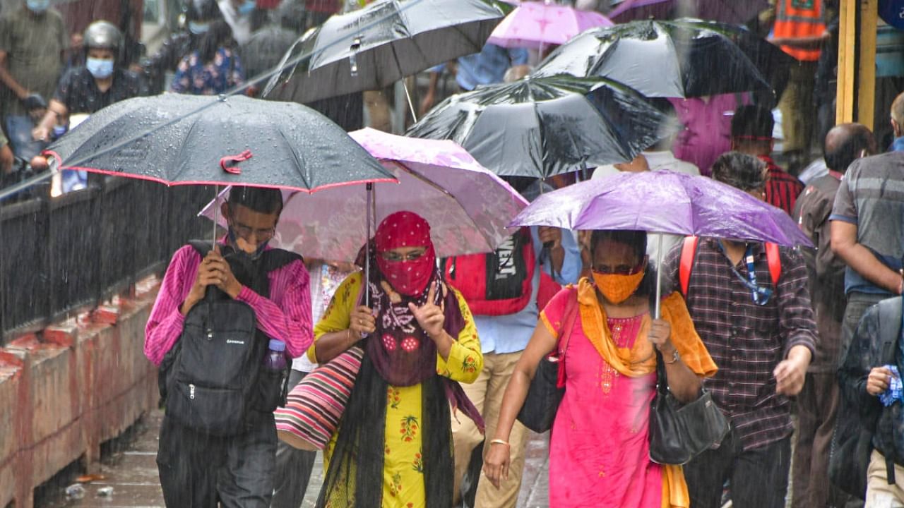 People hold umbrella cross the road during rain at CST, in Mumbai. Credit: PTI Photo