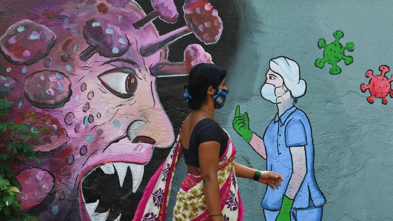 A pedestrian walks past a wall mural depicting a frontline medical staff stopping the Covid-19, in Navi Mumbai. Credit: AFP Photo