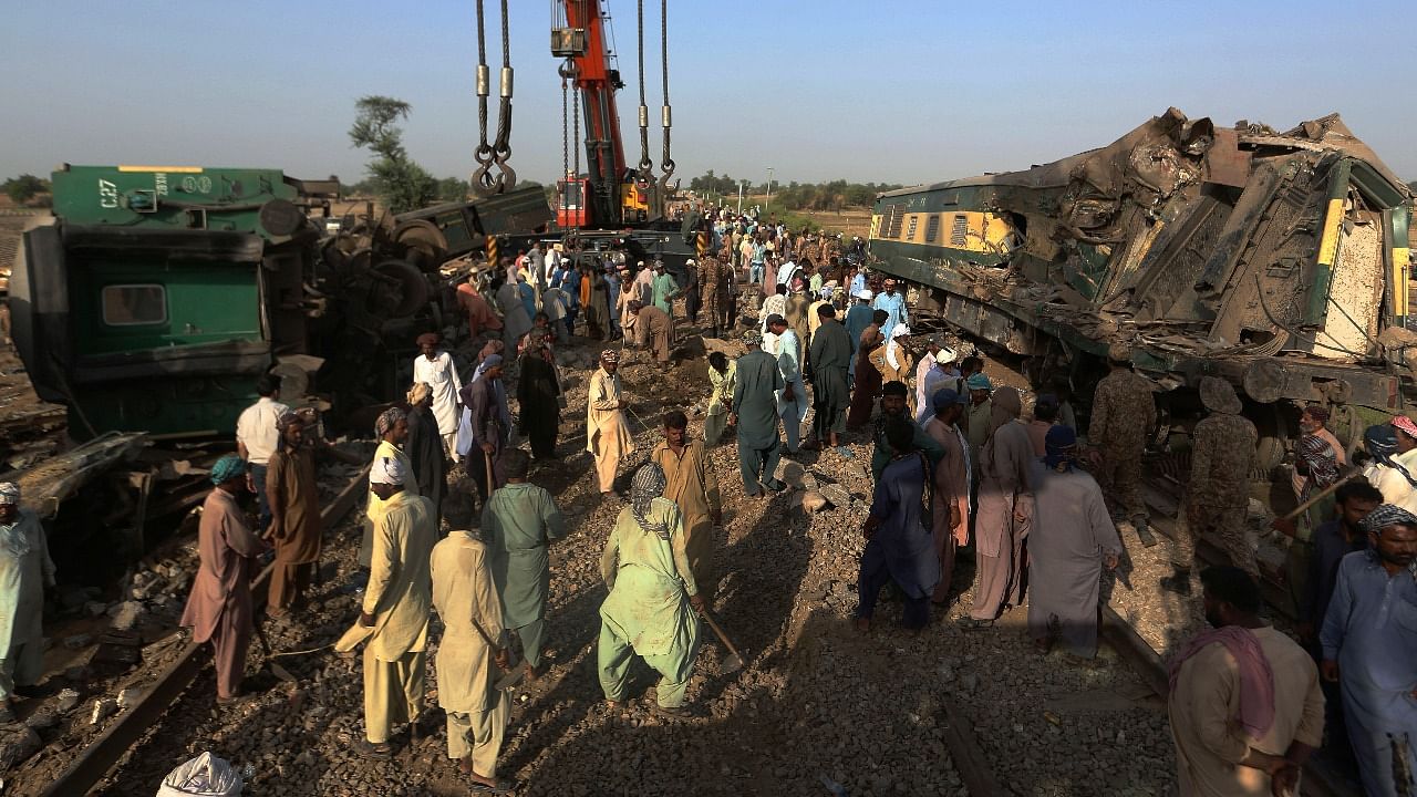 Railway workers remove wreckage to clear the track at the site of a train collision in the Ghotki district, southern Pakistan. Credit: AP/PTI Photo