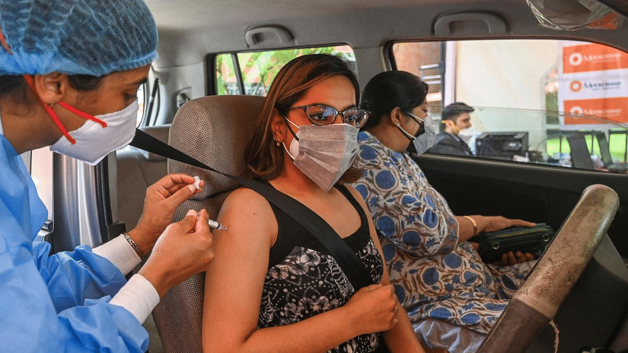 A health worker inoculates a woman with a dose of the Covaxin vaccine at a drive-in vaccination center in Moolchand hospital in New Delhi. Credit: AFP Photo