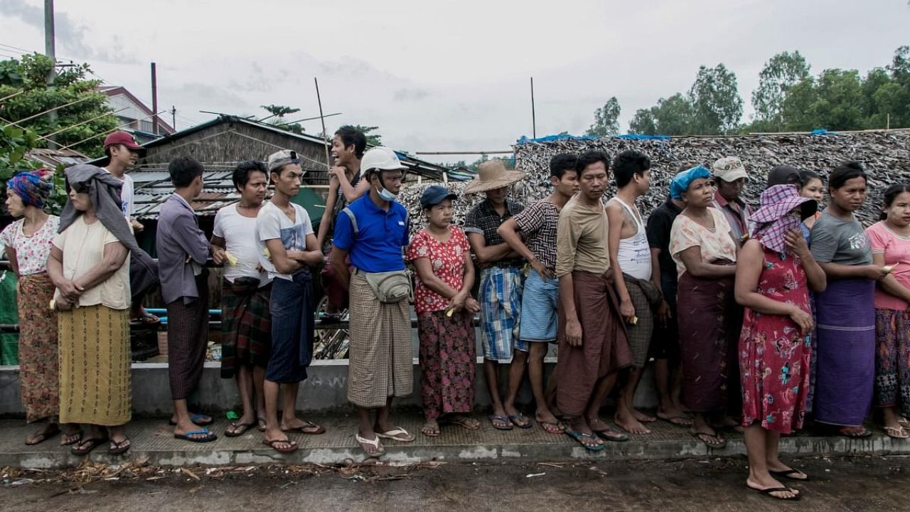 People wait to receive bags of rice distributed by the World Food Programme (WFP) as part of food aid efforts to support residents living in poor communities on the outskirts of Yangon. Credit: AFP Photo