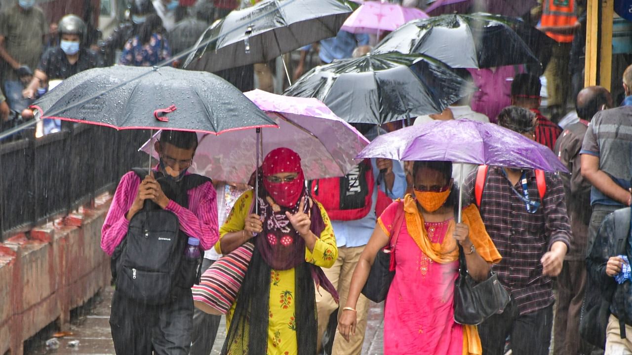 People hold umbrellas cross the road during rains at CST, Mumbai. Credit: PTI Photo