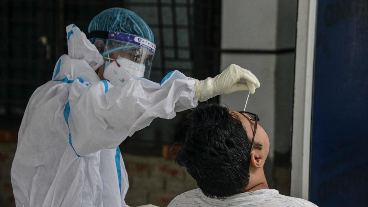 A health worker collects a swab sample for a RT-PCR Covid-19 coronavirus test at the North Bengal Medical college and hospital on the outskirts of Siliguri. Credit: AFP Photo