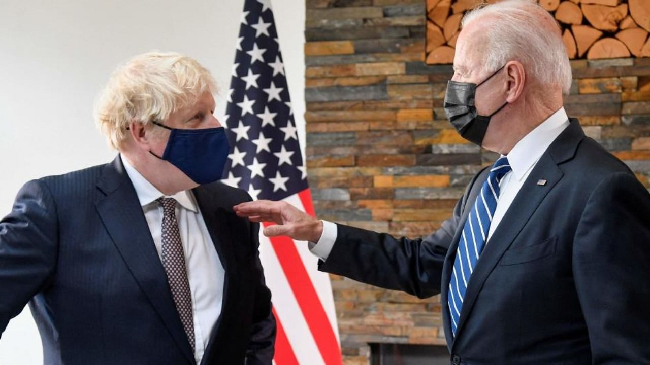 Britain's Prime Minister Boris Johnson (L) and US President Joe Biden, wearing face coverings due to Covid-19, view documents relating to the Atlantic Charter prior to a bi-lateral meeting at Carbis Bay, Cornwall on June 10, 2021. Credit: AFP Photo