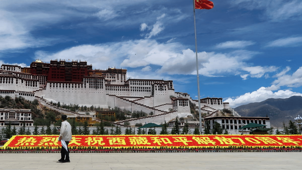 A man stands in front of a sign marking 70 years since Chinese rule over Tibet. Credit: Reuters Photo